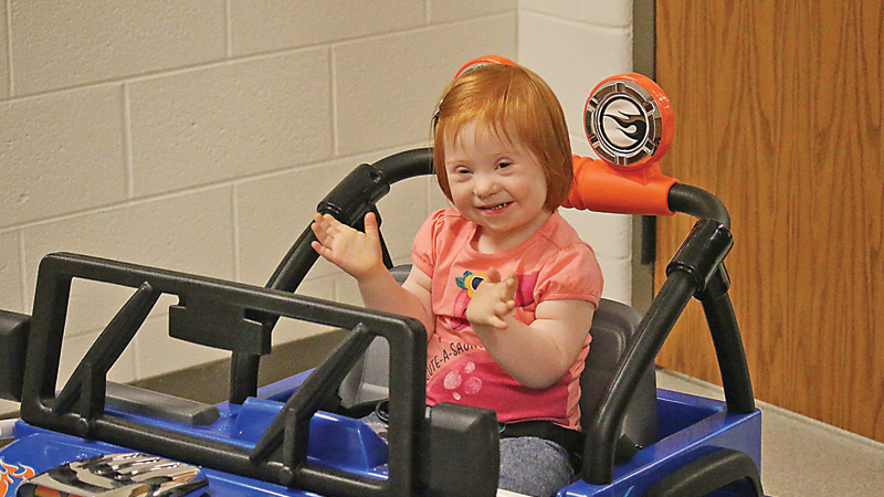 Anna Grace Mathews is all smiles after receiving her motorized vehicle inside the BD Phillips Building on the Milligan College campus